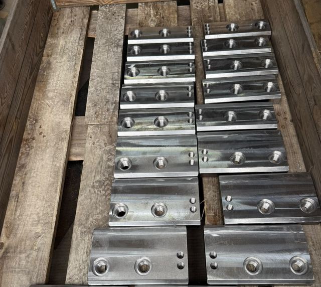 Holzkiste mit siebzehn gleichen gefrästen Stahlplatten